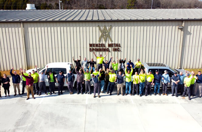 Large group of people waving in front of Wenzel Metal Spinning building.
