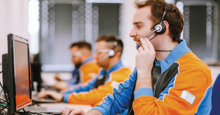 Customer service agents wearing headsets working at computers in a row